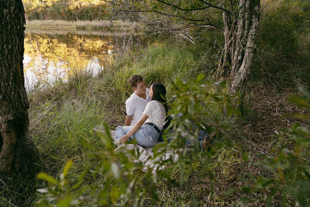 couple together by the water in their engagement photographs in east tx