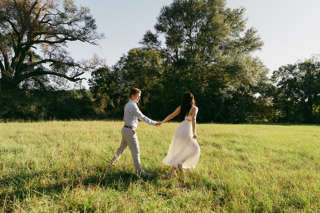 couple run together across field in their engagement photographs in east texas