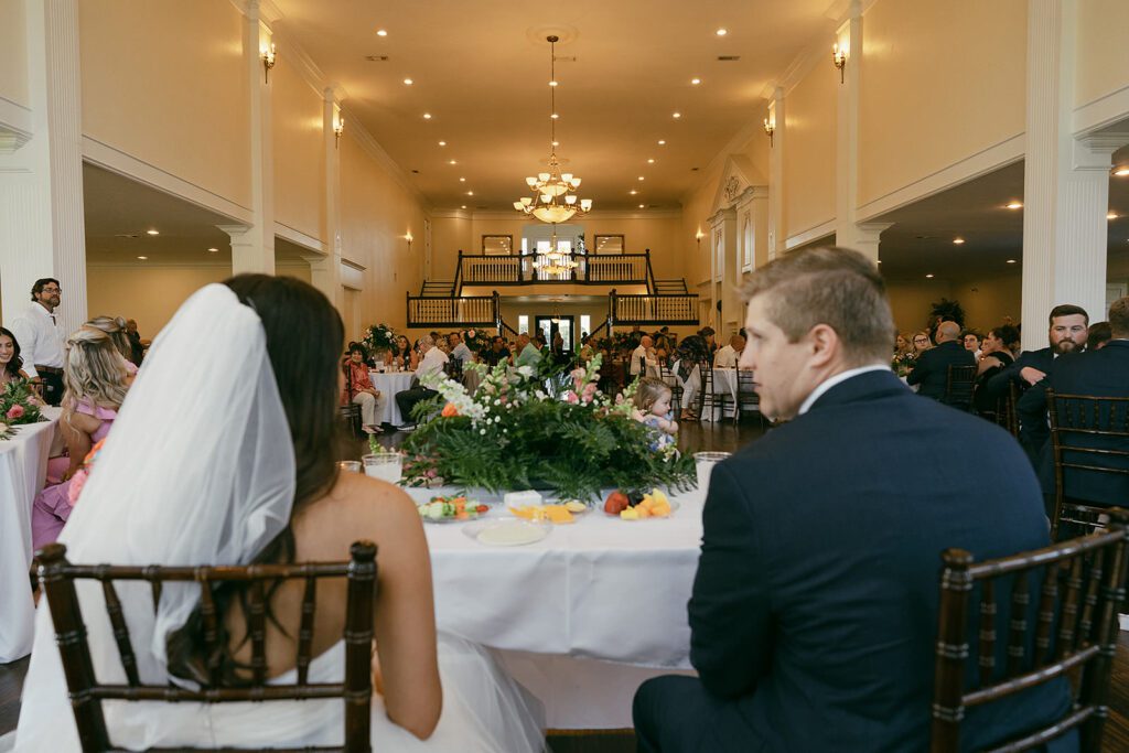 bride and groom sit down at the couples table at their reception at the springs in valley view tx