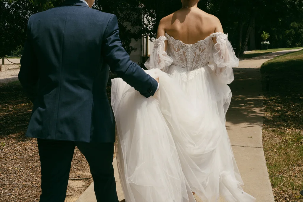 bride and groom walk together groom holds dress at the folmar in tyler texas