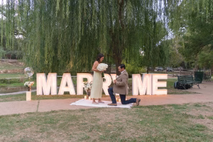 man kneels down under a willow tree at Landa Park to propose engagement